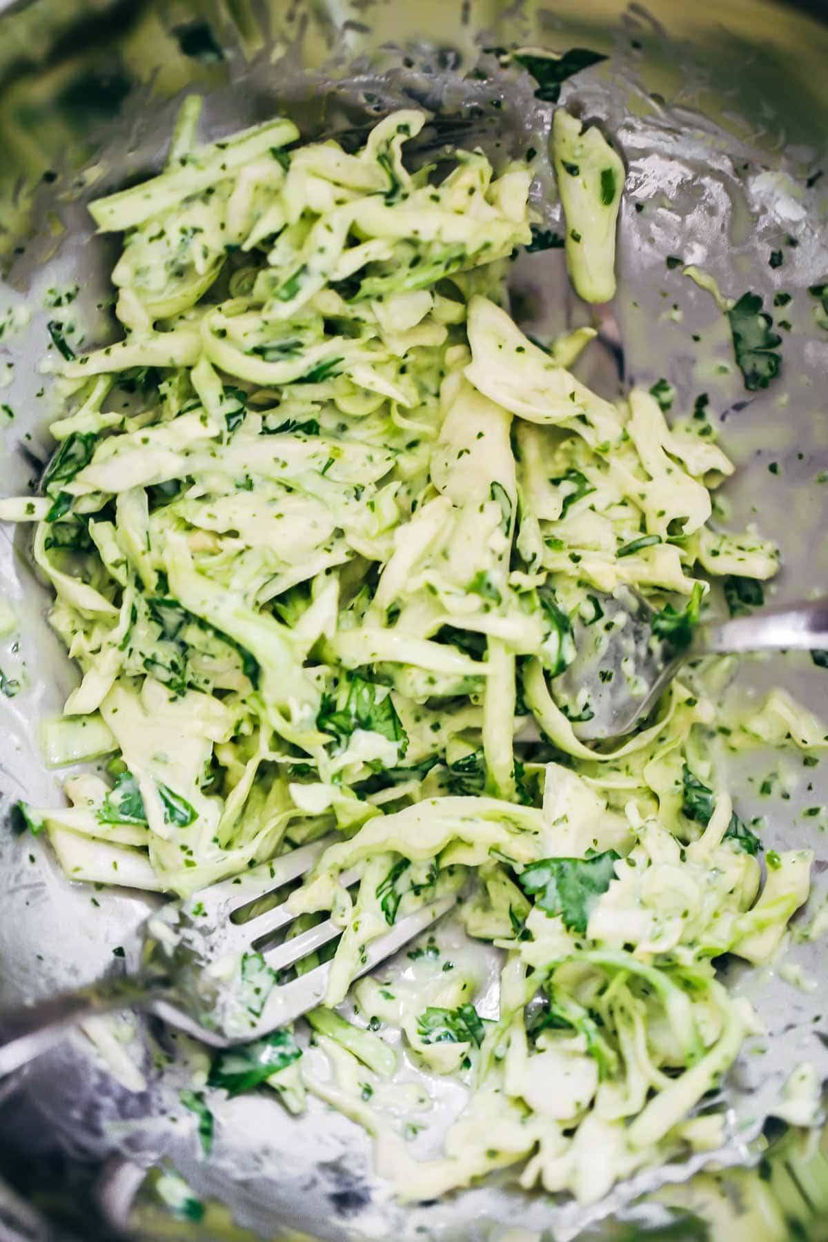 Garlic cilantro lime slaw in a bowl with forks.